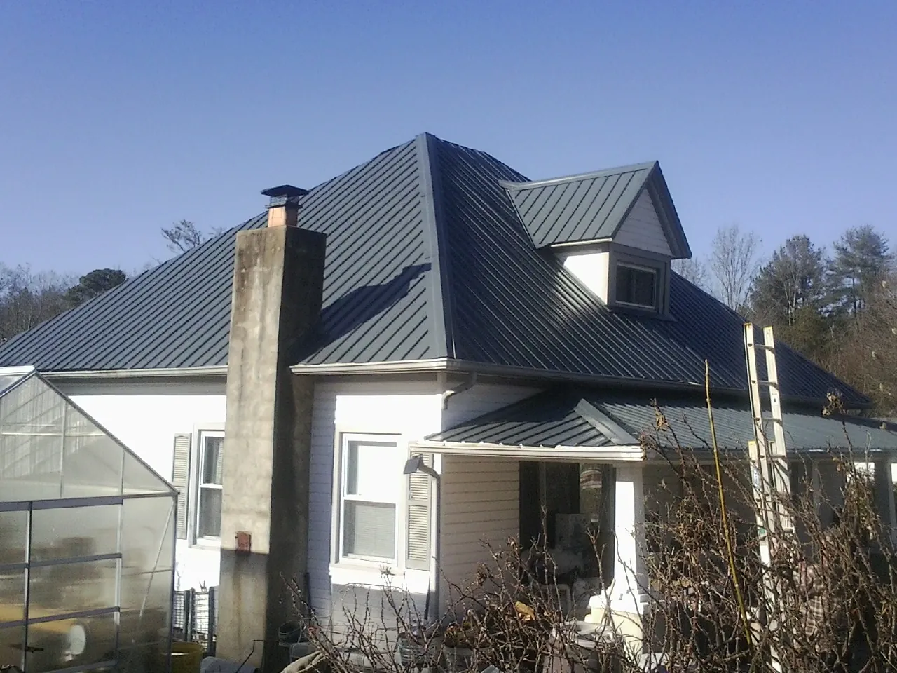 Dark blue standing seam metal roof on a white farmhouse with dormer — Slate & Tile Roof Repair by Roofing Brothers in Bruneau
