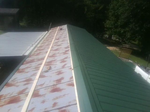 Old rusted panels beside newly installed green metal roofing — Wind Damage Roof Repair by Roofing Brothers in Bruneau