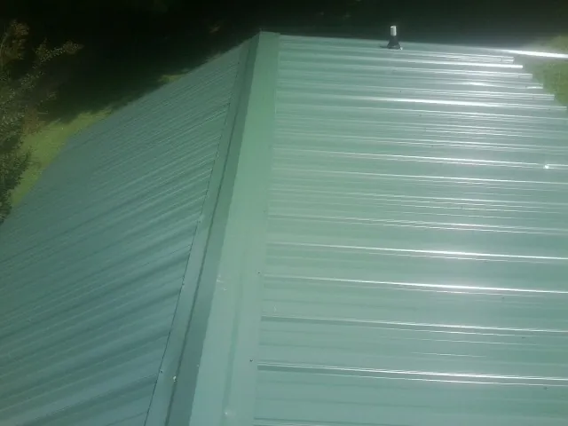 New green metal panels meeting at the ridge of a roof — Flat Roof Repair work by our crew in Bruneau