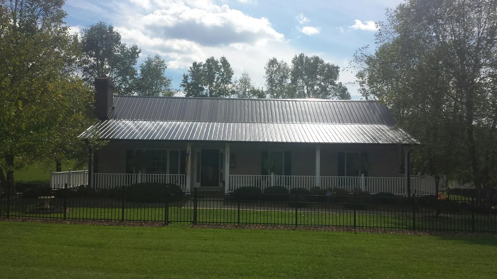 Gray metal roof on a brick ranch with a full width front porch — Gutter Guard Installation work by our crew in Bruneau