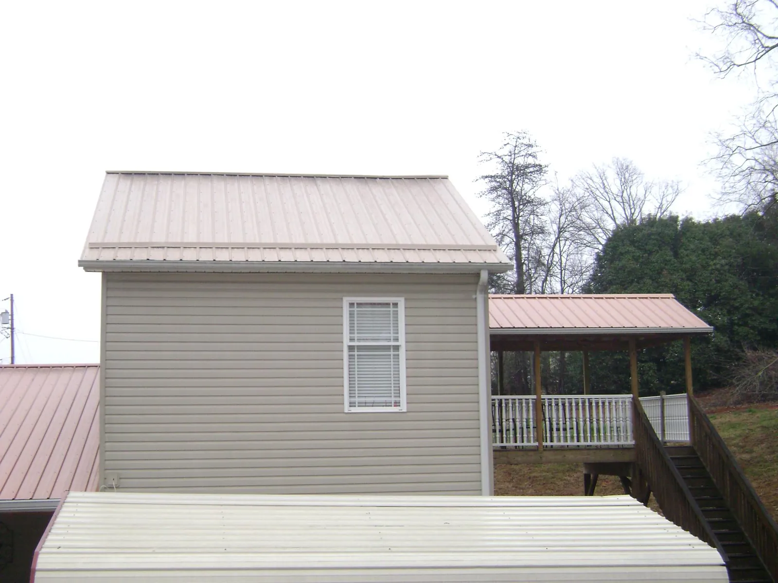 Tan metal roofs on a two story addition and attached porch, from a Roof Replacement job in Bruneau